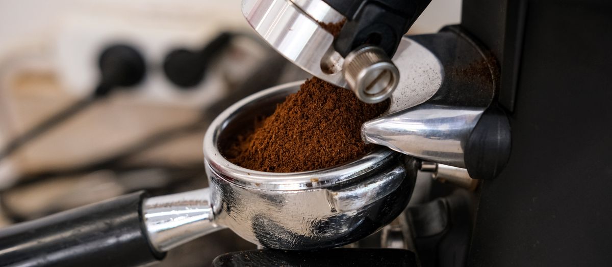 Detailed shot of an espresso machine dispensing fresh coffee grounds into a portafilter.