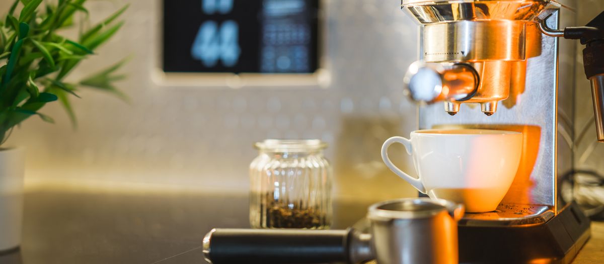 Espresso machine setup with coffee beans and mug on countertop, ideal for home baristas.